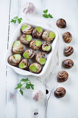 Escargots de Bourgogne over white wooden surface