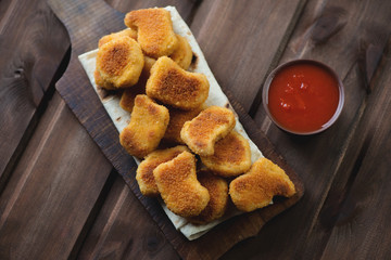 Chicken nuggets with dip sauce over rustic wooden background