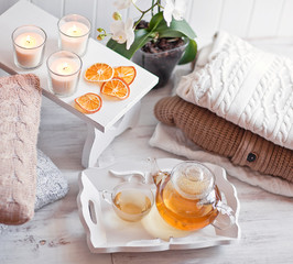 Tea-tray with hot grass drink, knitting clothes, dry oranges, ca