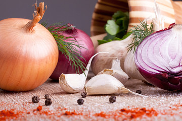 close up of garlic, onion fresh herbs on  wooden board