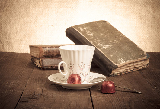 Cup of coffee, shokolad and stack of old books on the old wooden