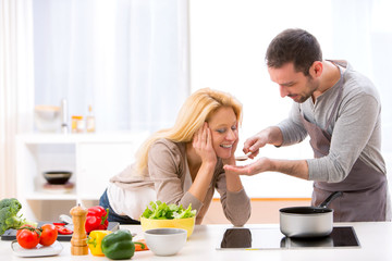 Young attractive woman give food to her husband to taste