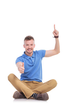 young casual man points up and gives thumb up