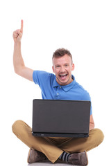 young seated man with laptop points up