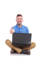 young seated man with laptop show thumb up