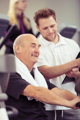 trainer erklärt einem älteren mann das fitness-gerät