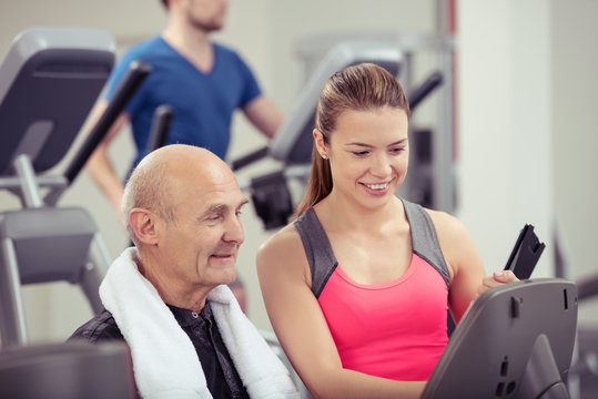trainerin im fitness-studio berät einen älteren kunden