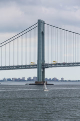 White Sailboat Under Suspension Bridge