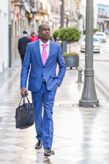 Black businessman walking on the street with a modern briefcase