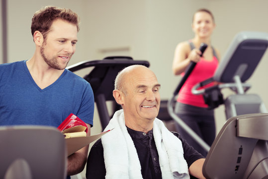 trainer und älterer mann im fitness-studio