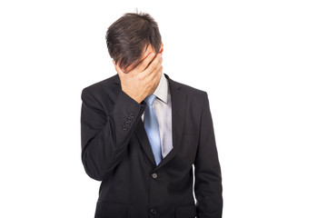 Portrait of exhausted young businessman covering his face with h