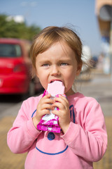 Adorable little girl eating an ice cream outdoors