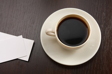 A cup of coffee and business cards on a desk