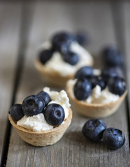 Blueberry tartlets on rustic wooden kitchen background