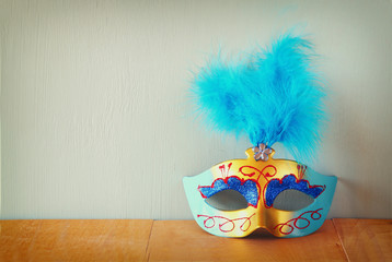 Venetian masquerade mask on wooden table. retro filtered image  