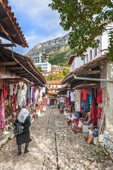 Elderly woman walking along the bazaar ok Kruja - 76732445