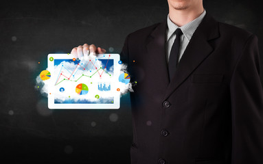 Person holding a touchpad with cloud technology and charts