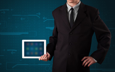 Businessman holding a white modern tablet with blurry apps