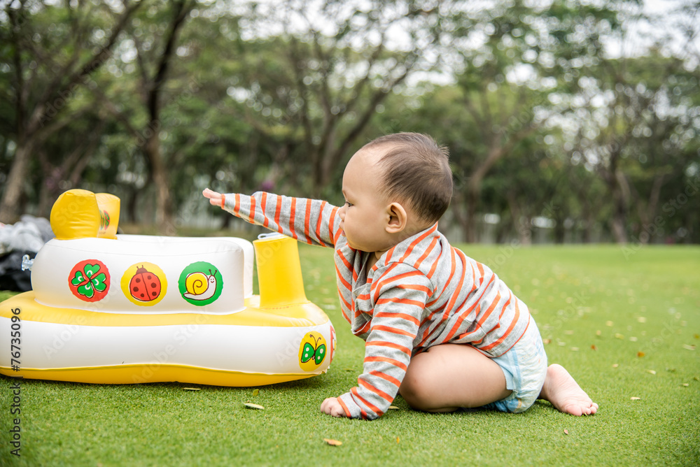 Wall mural baby playing on the grass field in the park