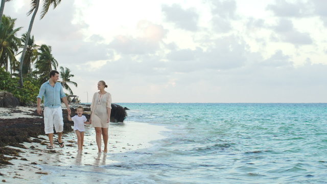 Parents and child walking along the beach holding hands
