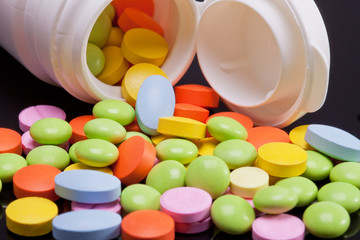 lot of colorful pills with white box on black background