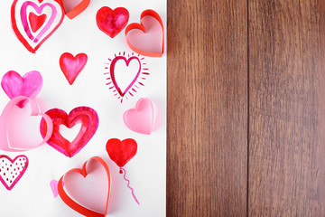 Painted hearts on sheet of paper on wooden table background