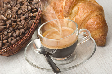 coffee in glass cup with croissants and coffee beans