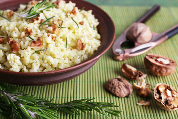 Rice with walnuts and rosemary in plate on bamboo mat