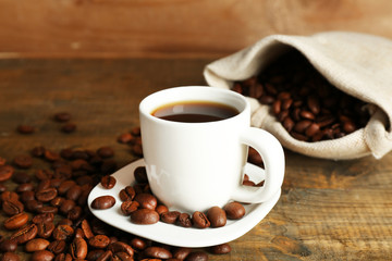 Obraz premium Cup of coffee with beans on rustic wooden background