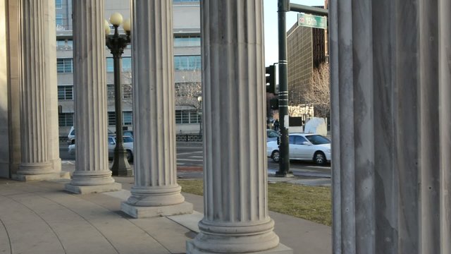 Pan shot through Roman columns to the city traffic