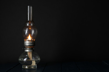 Kerosene lamp on wooden table and dark background