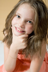 милая девочка улыбается, облокотившись на руку