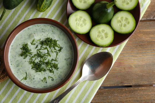 Cucumber soup in bowl on rustic wooden table background