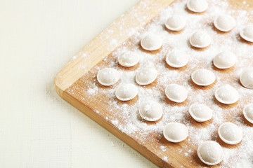 Raw dumplings on cutting board on table close-up