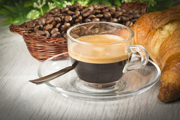 coffee in glass cup with croissants and coffee beans