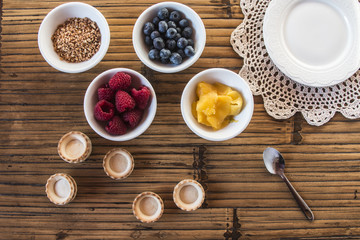Cooking sweet tartlets with raspberry, blueberries, mango and nu