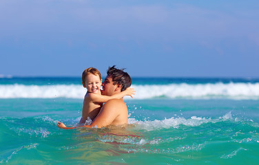 happy father and son having fun in water waves