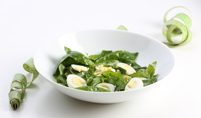 Salad with quail egg and basil in plate isolated on white