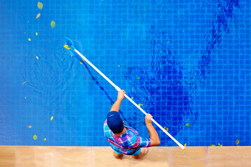 young adult man, personnel cleaning the pool from leaves