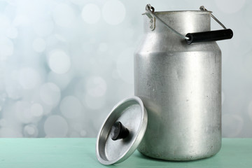 Retro can for milk on wooden table on light background