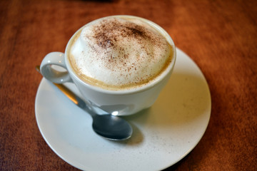 Delicious foamy cappuccino on the wooden table