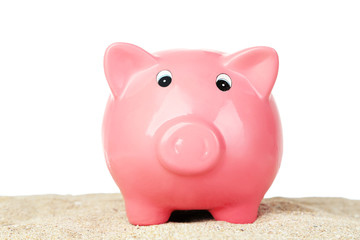 Piggy bank on sand, on white background