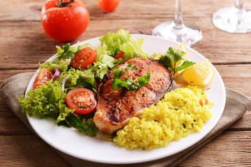 Tasty baked fish with rice on plate on table close-up