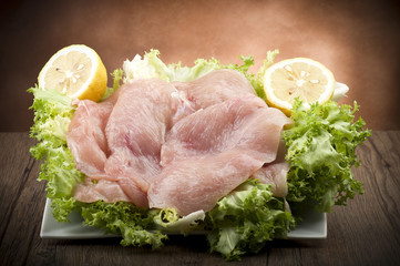 slices of chicken with salad on wood