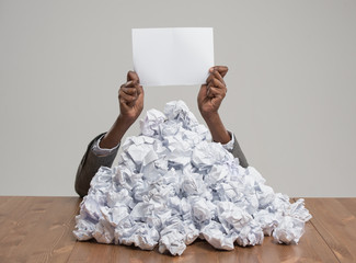 Business woman under crumpled pile of papers