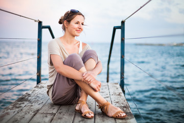 Portrait of a young woman on a jetty at the seacoast while on va