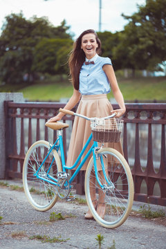 Young beautiful, elegantly dressed woman with bicycle in the par