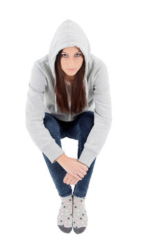 Happy hooded girl with grey sweatshirt sitting on the floor