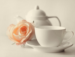 Delicate roses beside a white cup