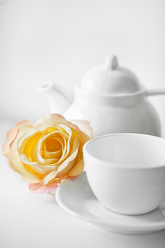 Delicate roses beside a white cup